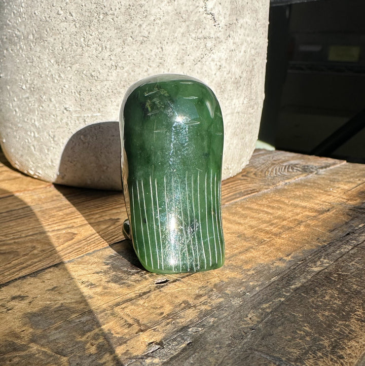 Back view of the 2-inch green jade owl figurine on a wooden surface