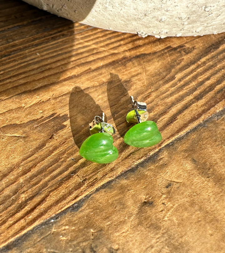 Pair of green heart shaped earrings with silver findings on rustic wood