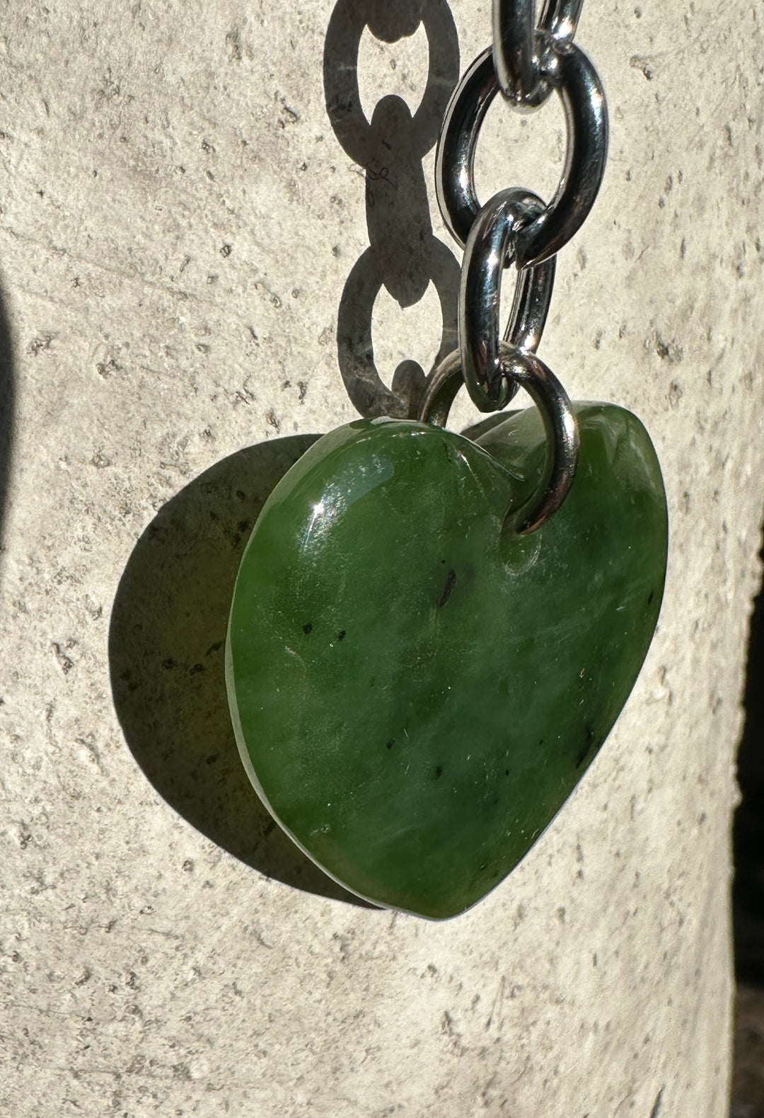Green heart shaped stone keychain charm attached to a silver chain and rings