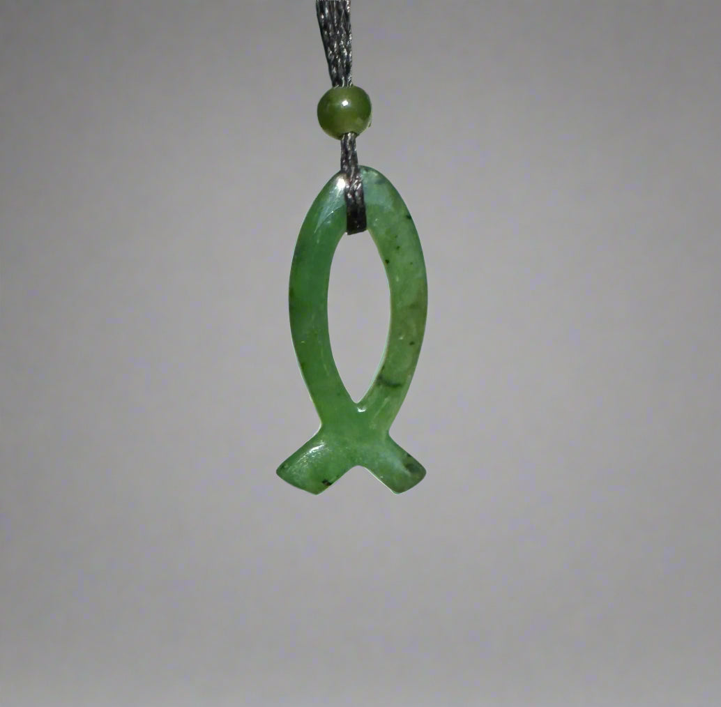 Green jade Ichthys pendant 30mm on a black cord with a round bead above against a gray backdrop.
