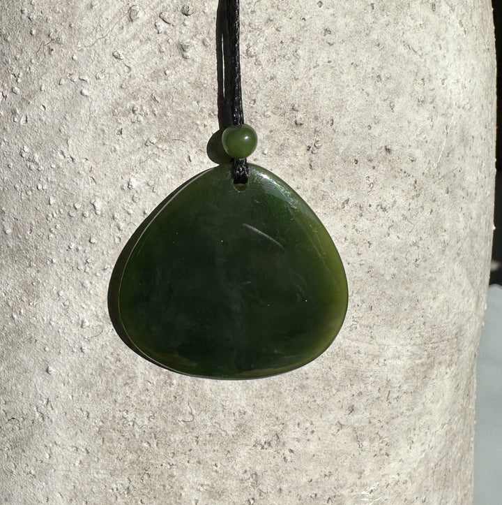 Dark green jade teardrop pendant suspended from a black cord with a small bead above it
