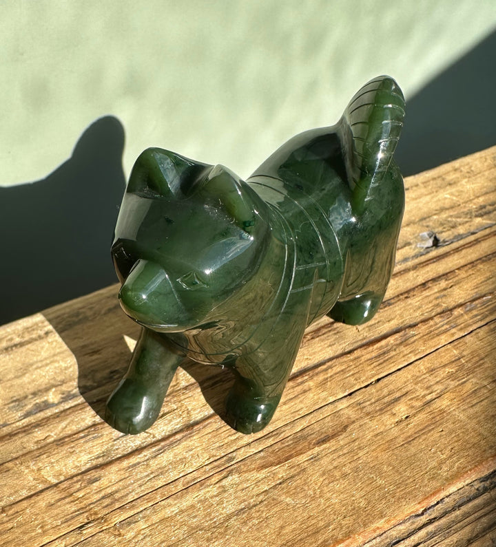 Small green jade husky figurine resting on a sunlit wooden surface