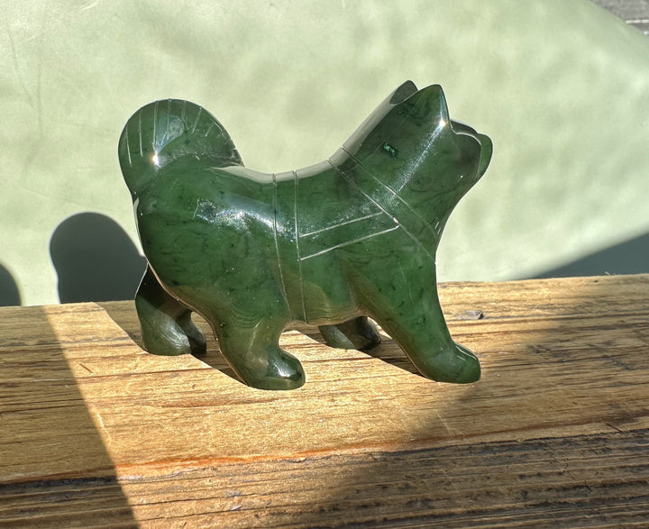 Canadian Jade Husky dog sculpture in dark green stone on a wooden surface