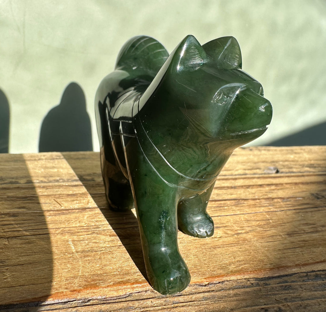 Three inch green jade husky dog statue on a wooden surface outdoors
