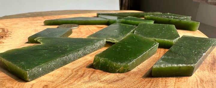 Several translucent green rectangular blocks or slabs arranged on a round wooden slab, with a coin visible for scale.