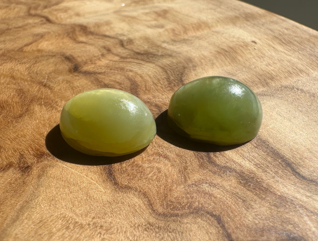 Three oval green Siberian Cats Eye cabochons arranged on a wooden background