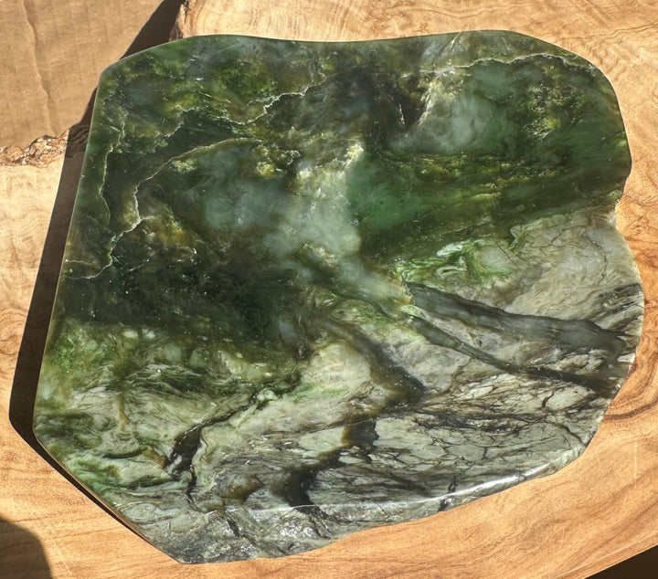 Top view of the Canadian Jade Dish showing glossy green stone with varied patterns on a wooden table