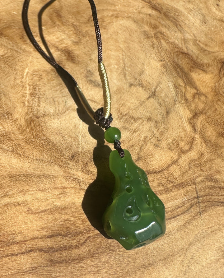 Close-up of a rich green Siberian Abstract Pendant 21.5mm on a black braided cord