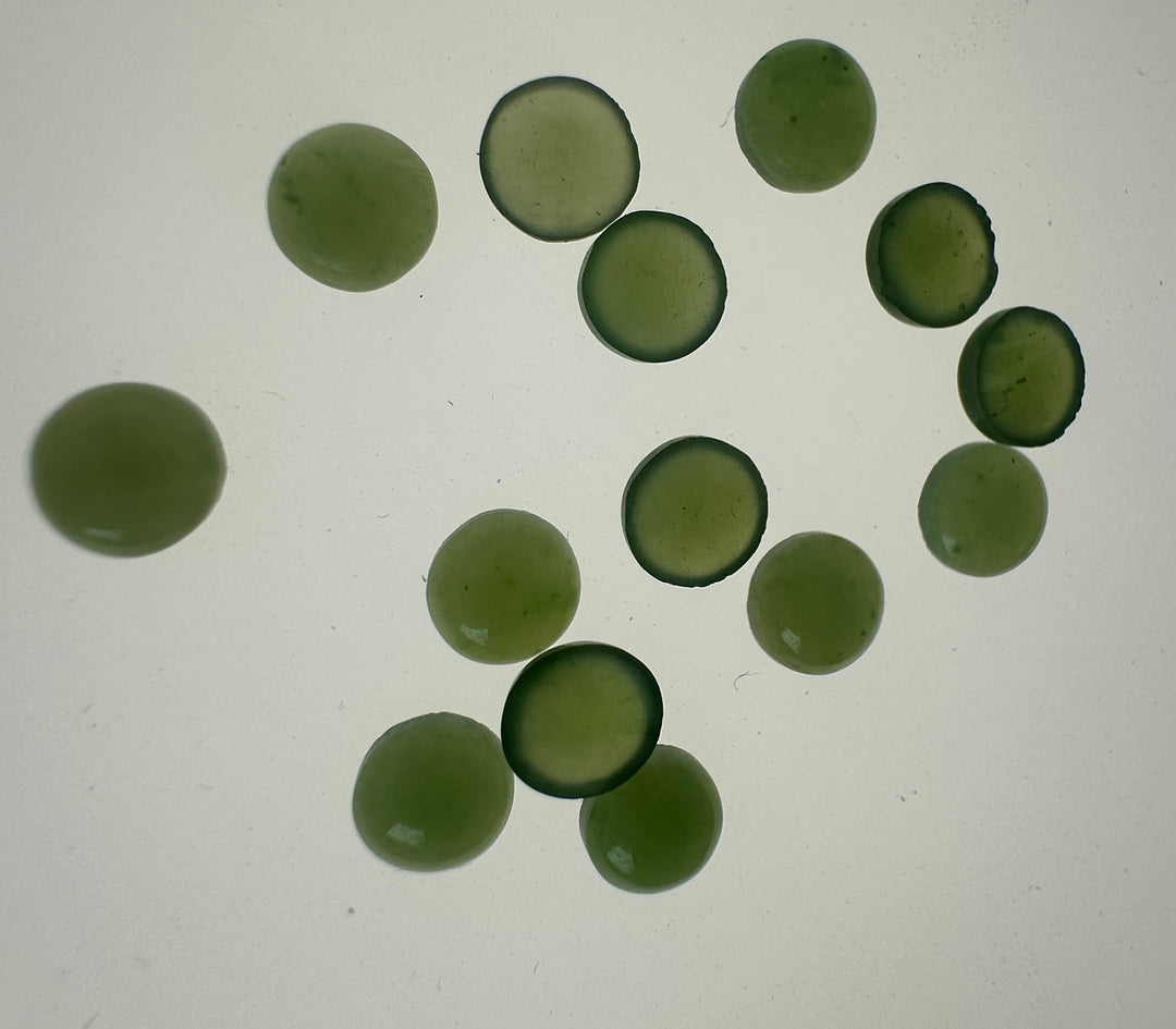 Vintage light green Canadian jade round cabochons scattered on a pale background