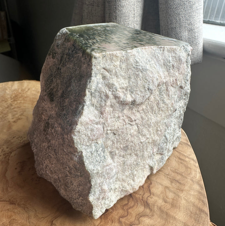 wyoming white green and pink rough on a wooden base beside a windon