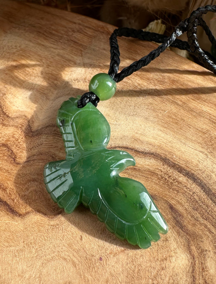 Green jade eagle pendant on a black braided cord with a round bead