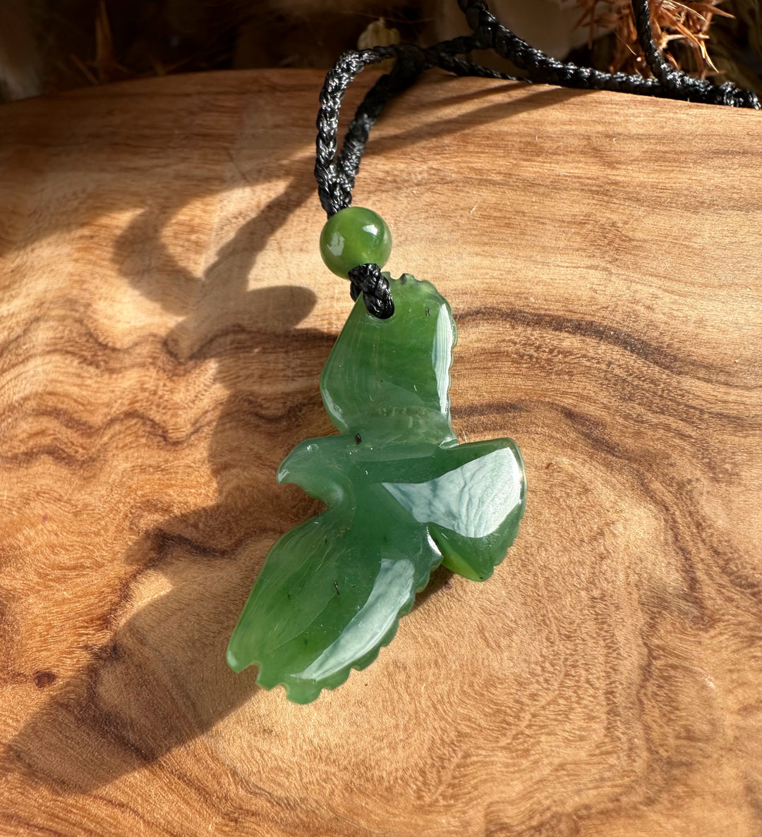 Green jade eagle pendant with round bead on a black braided cord necklace