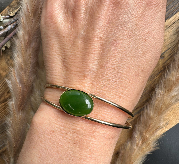 Wrist shot of Vintage Jade Bracelet featuring a green oval jade on a gold-tone double-band cuff