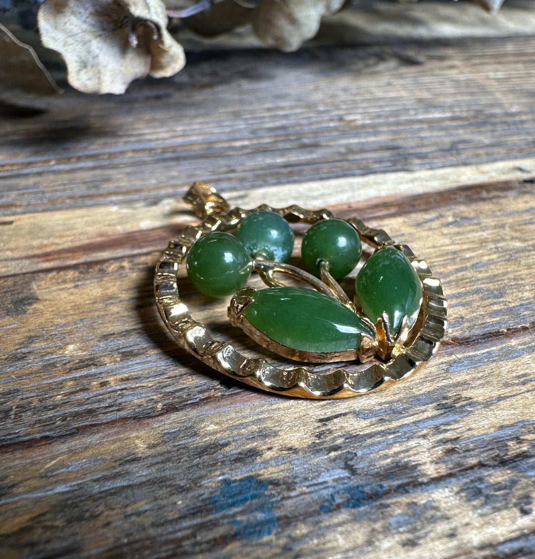 Vintage jade flower pendant on weathered wood showing round beads and leaf shaped inlays