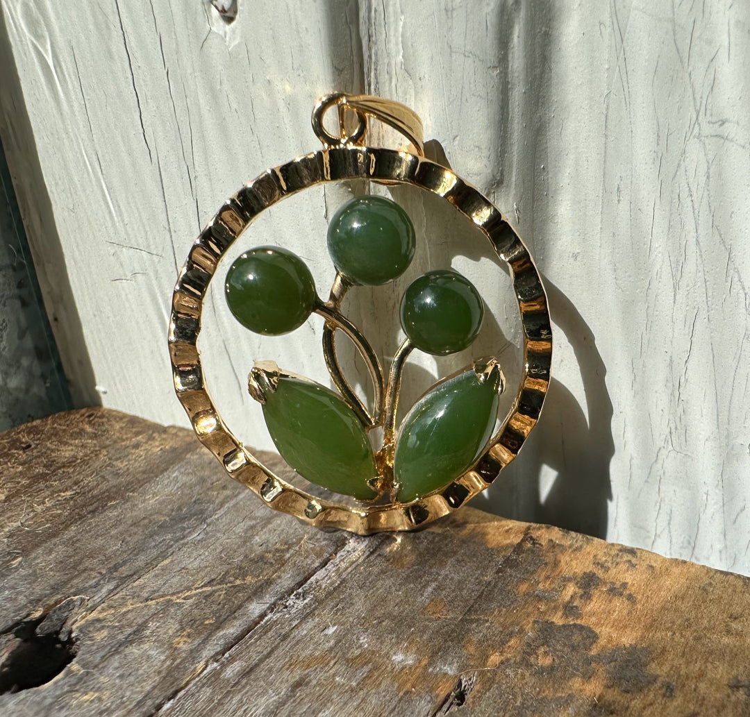 Gold circular pendant with a jade flower motif featuring three buds and two leaves