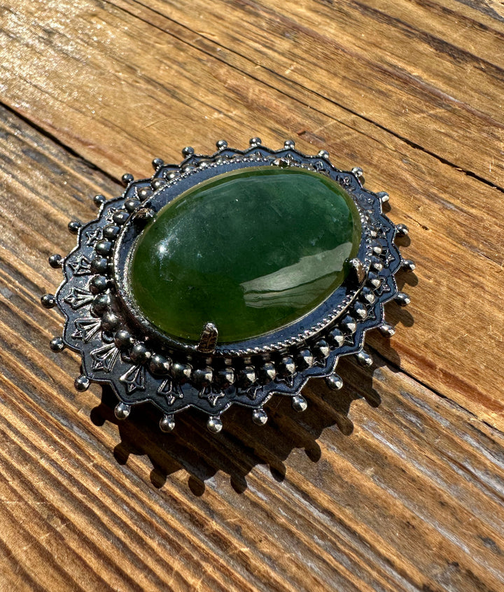 Vintage Jade Oval Brooch with green cabochon in an ornate dark metal filigree setting.