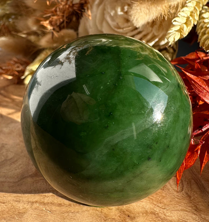 Canadian Jade Sphere 50mm on a wooden surface with dried floral accents in the background