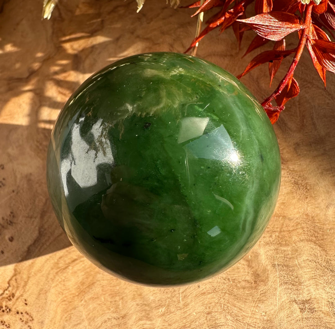 Canadian Jade Sphere 50mm polished green ball resting on a wooden surface