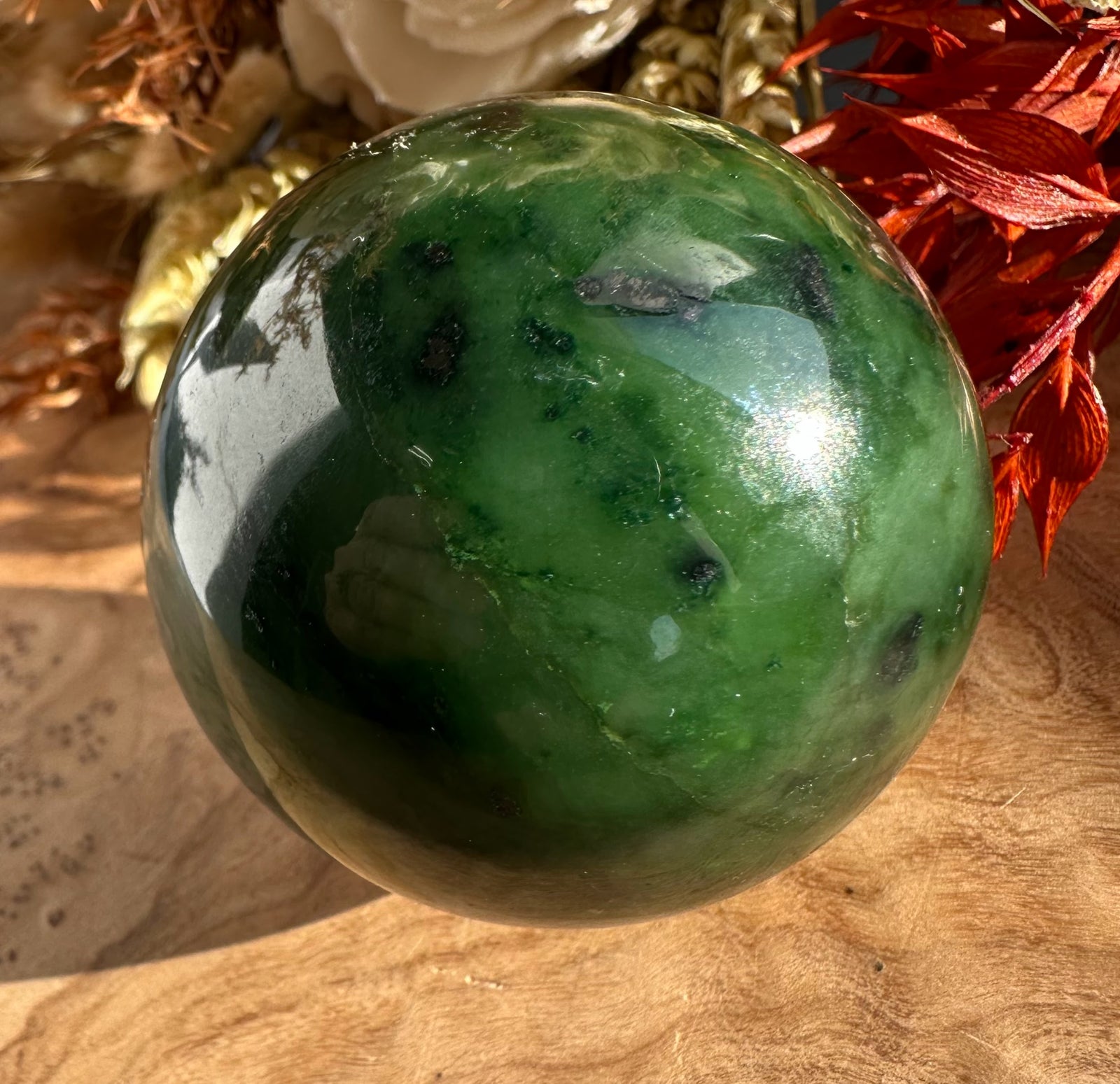 Canadian Jade Sphere 50mm polished green ball with red leaves in the background