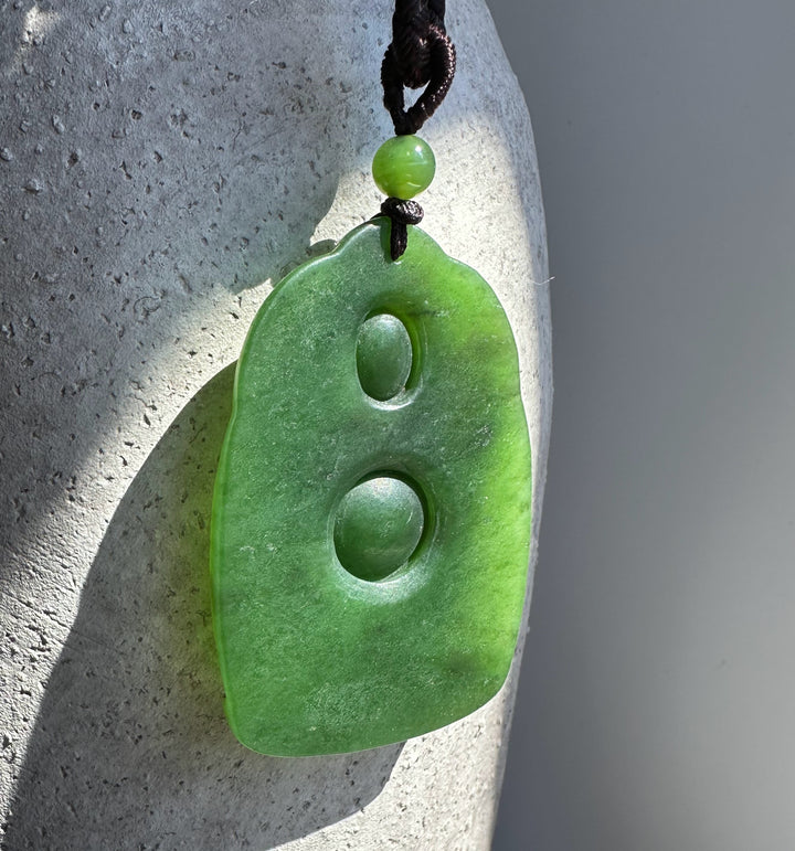 Green jade Ganesha Buddha pendant 57mm on a brown cord with a small green bead and two circular indentations