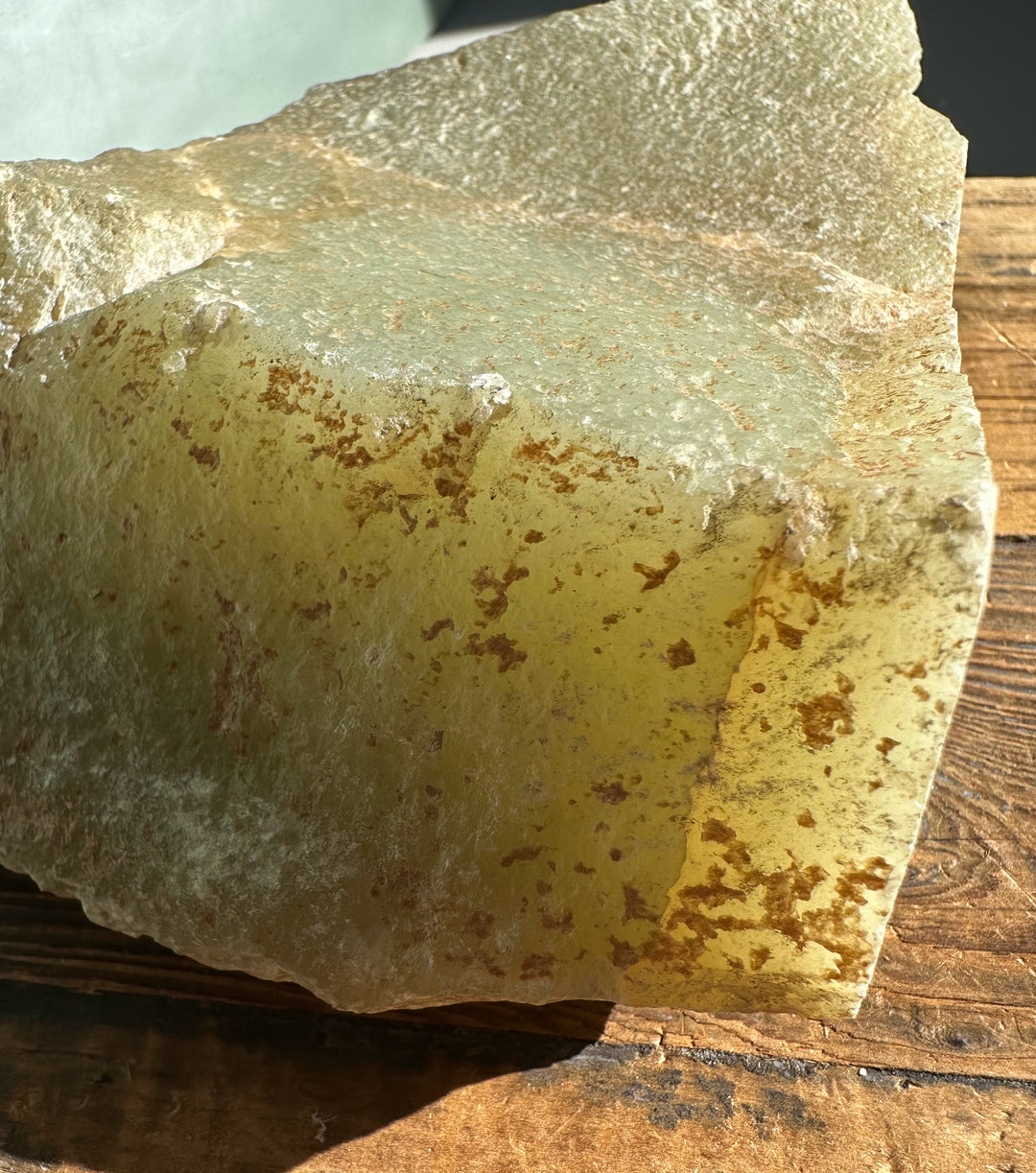 Korean jade rough showing a pale green face with brown specks and layered crust.