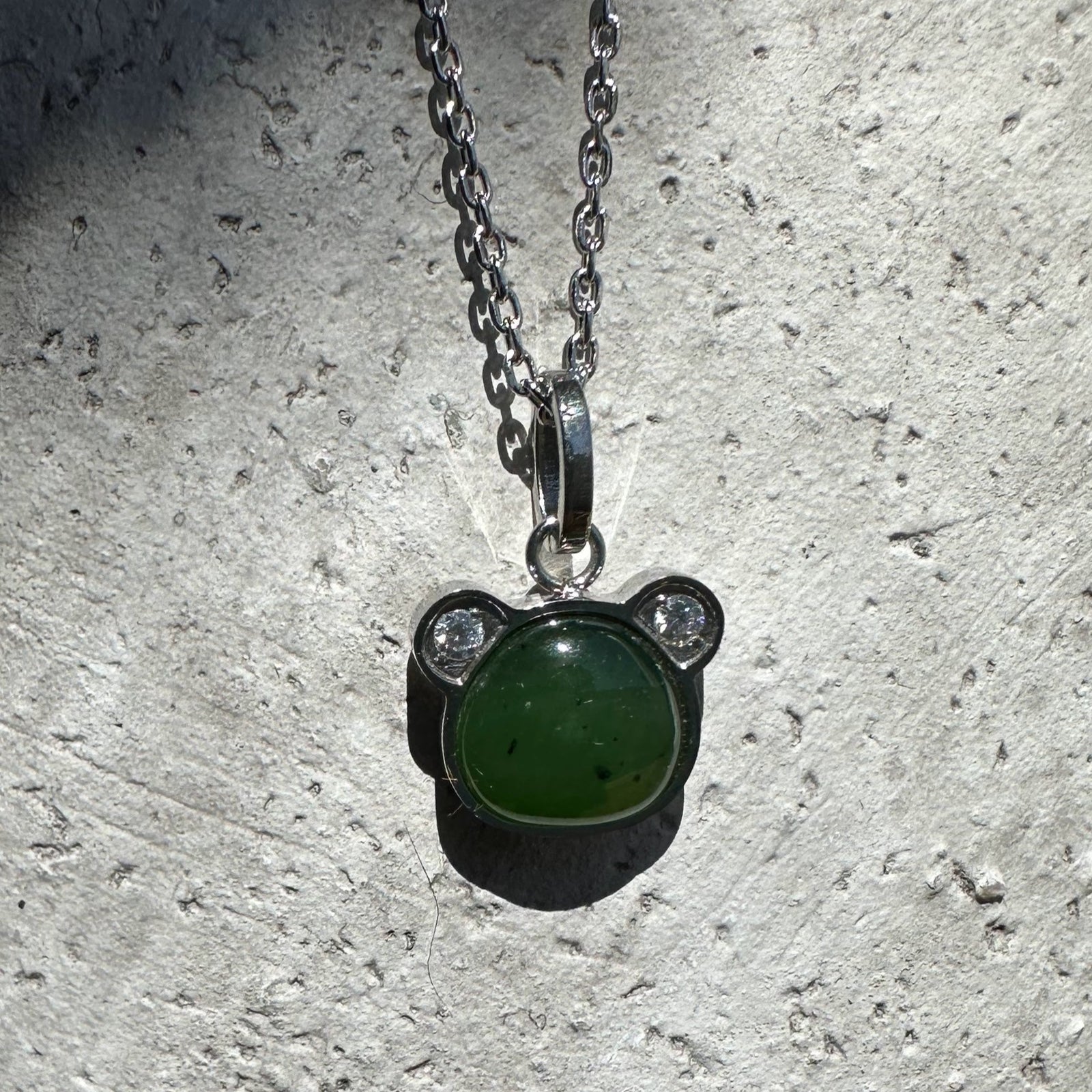 Green nephrite jade teddy bear pendant in a silver bear shaped setting on a chain