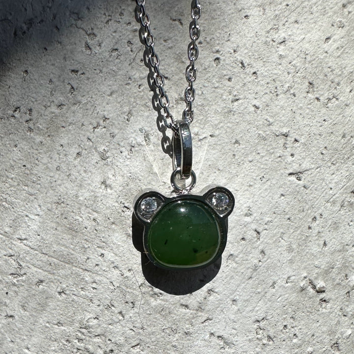 Green nephrite jade teddy bear pendant in a silver bear shaped setting on a chain