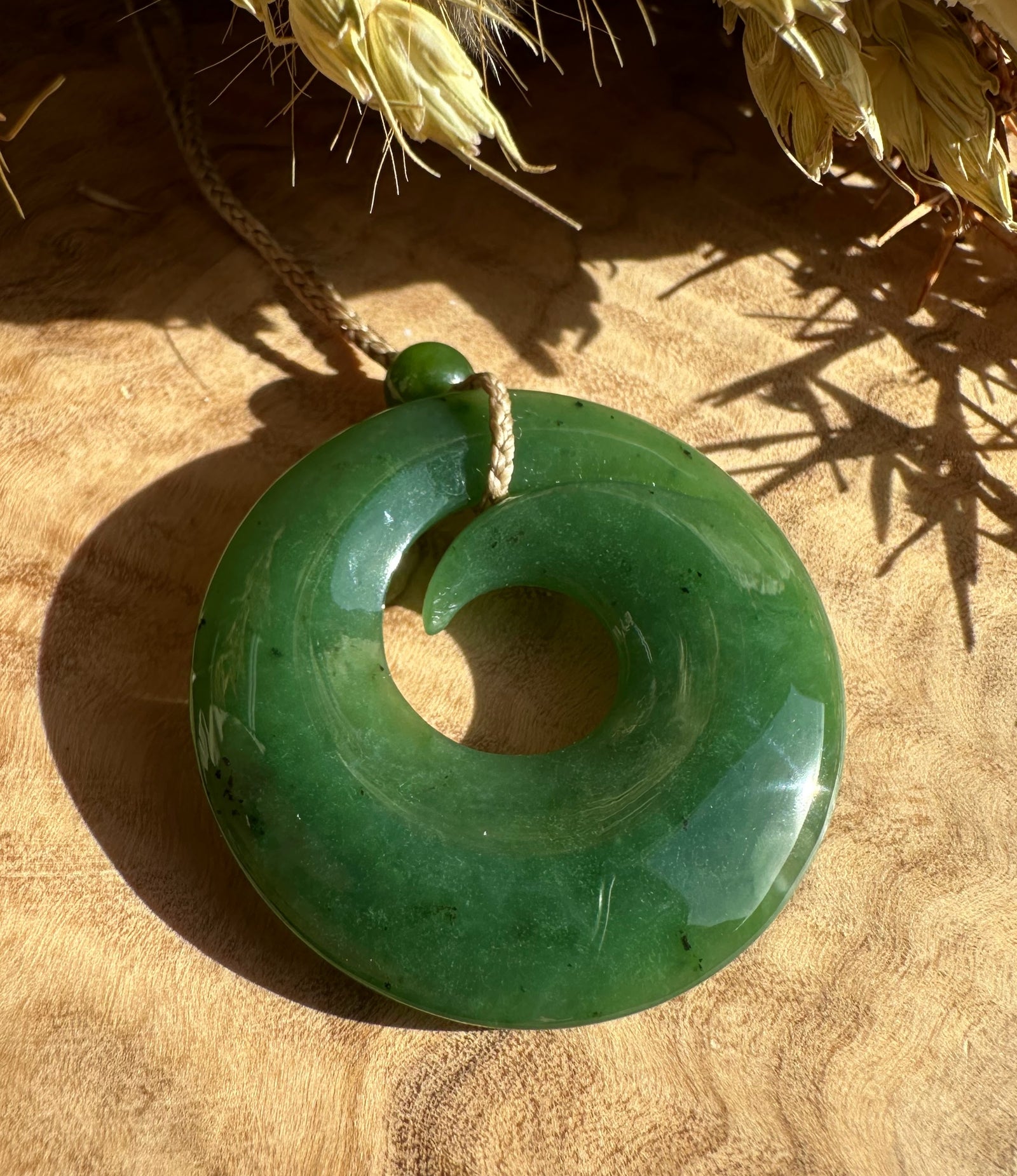 Donut shaped green pendant with a central hole hanging from a cord.