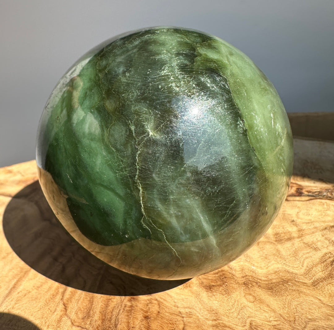 Canadian Jade 80mm sphere with varying green hues and natural markings