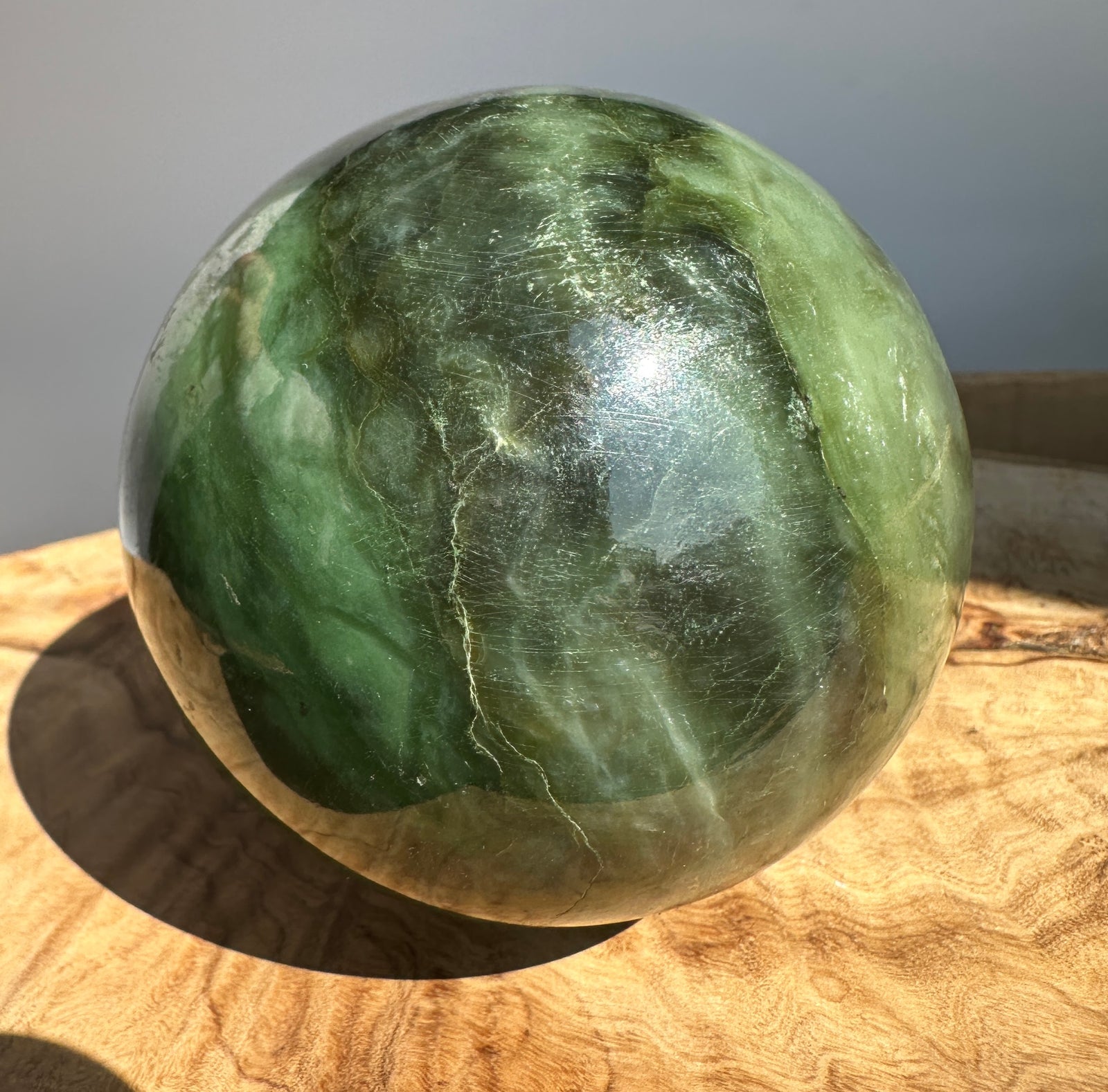 Canadian Jade 80mm sphere with varying green hues and natural markings