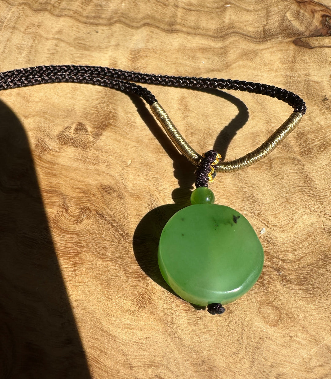 Apple green 16mm Siberian jade pendant on a dark braided cord with gold accent bead
