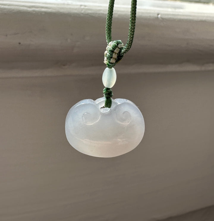Green braided cord with pale jade bead knot and a carved round jade pendant below.