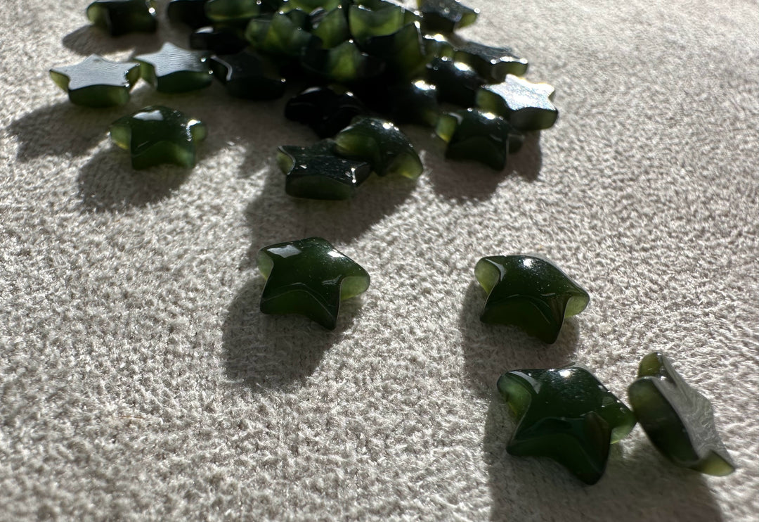 Group of dark green jade star cabochons laid out on a light surface with soft shadows