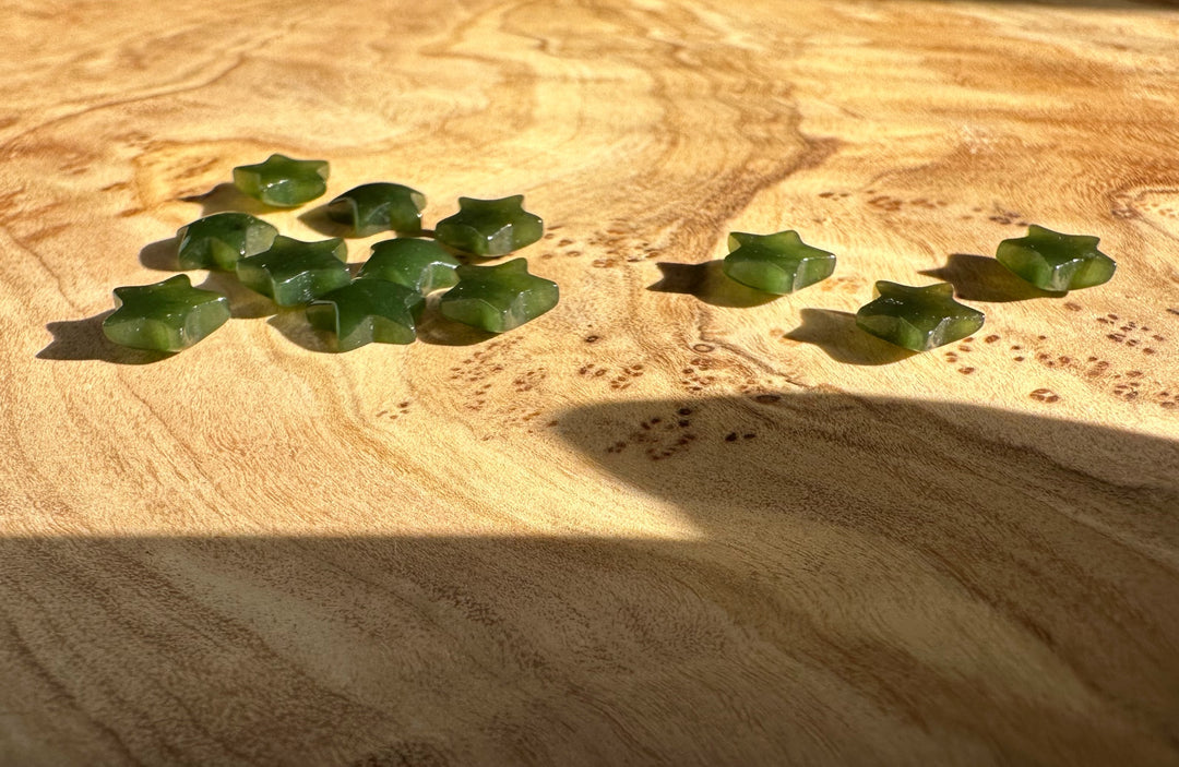 Dark green star shaped jade cabochons scattered on a warm wooden surface