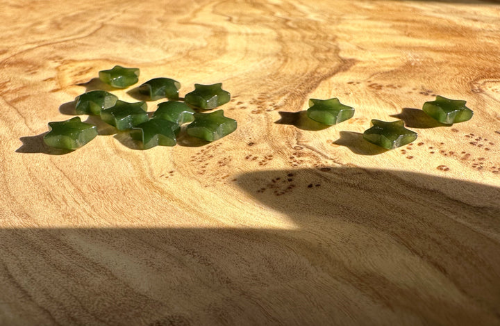 Dark green star shaped jade cabochons scattered on a warm wooden surface