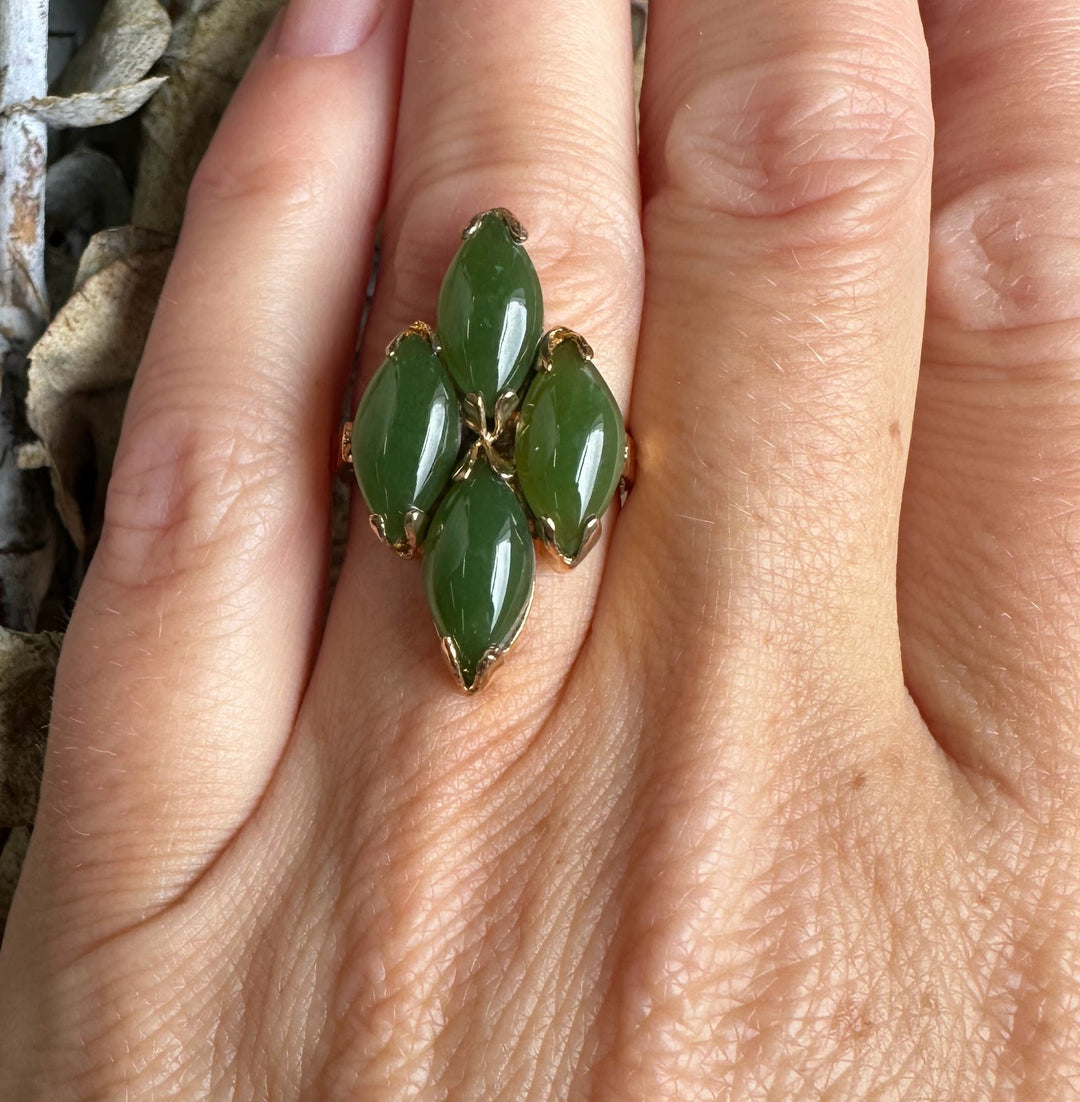 Hand wearing vintage jade ring featuring a cluster of five green marquise stones in a gold setting