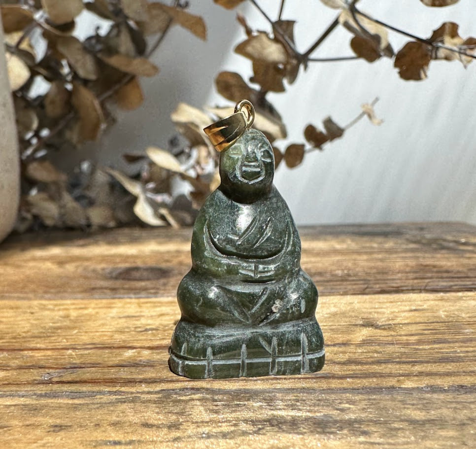 Dark green jade Buddha pendant with a gold bail, seated figure carved in smooth stone.