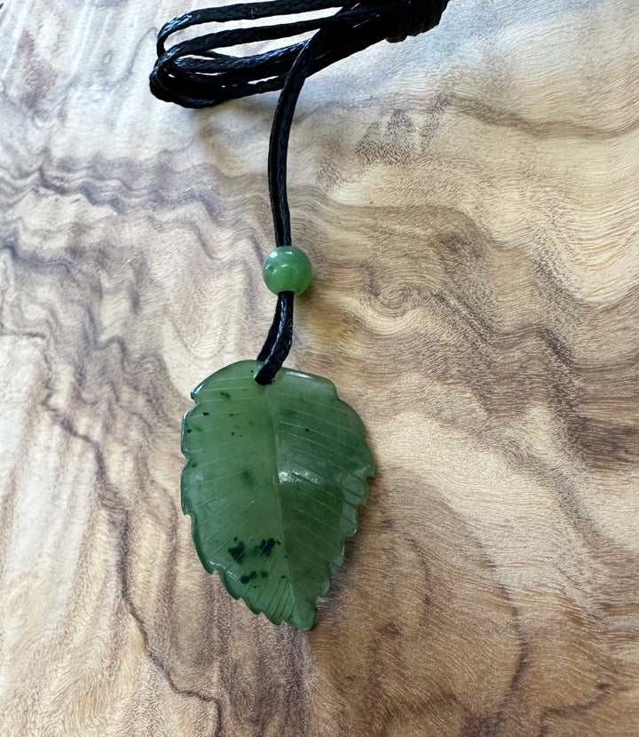 Close up of Canadian green jade leaf pendant on black cord with a small round bead above the leaf.