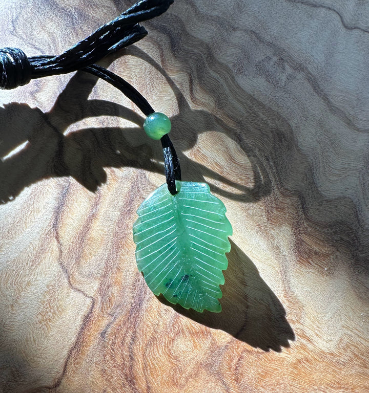 Front view of Canadian green jade leaf pendant on black cord necklace with bead above, showing leaf veins.
