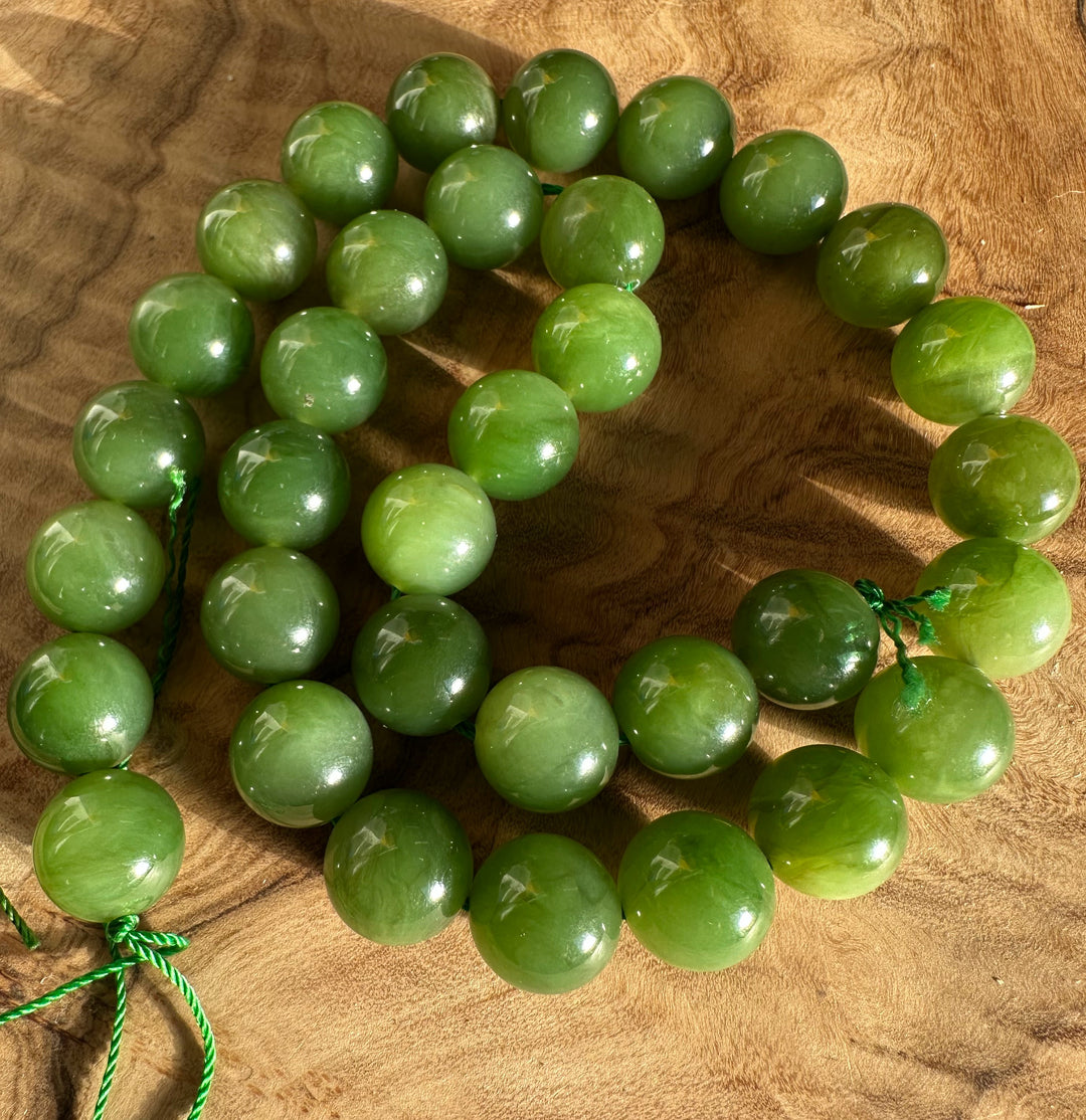 Light green Canadian 12mm beads arranged in a circular strand on a wooden surface