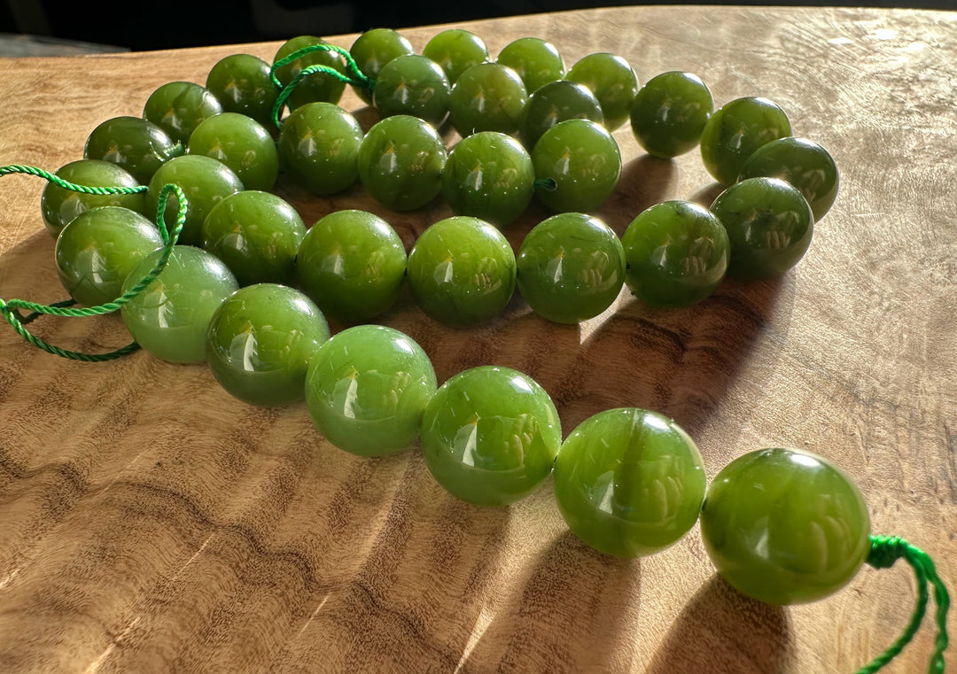 Light green 12mm beads with green cords laid on a wooden surface