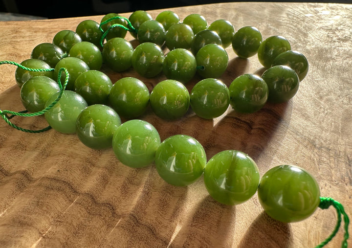 Light green 12mm beads with green cords laid on a wooden surface