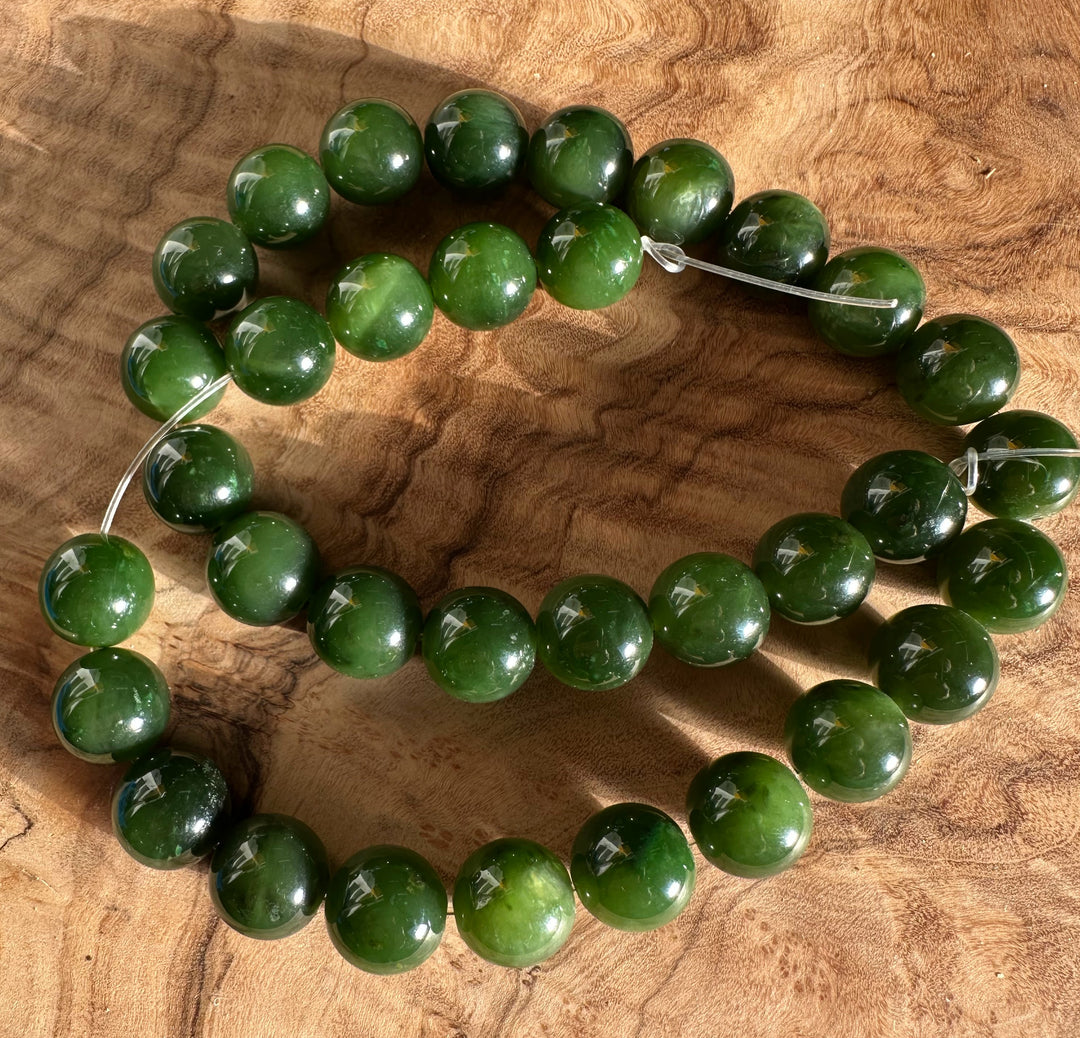 12mm Cassiar Jade unstrung beads laid on a wooden surface