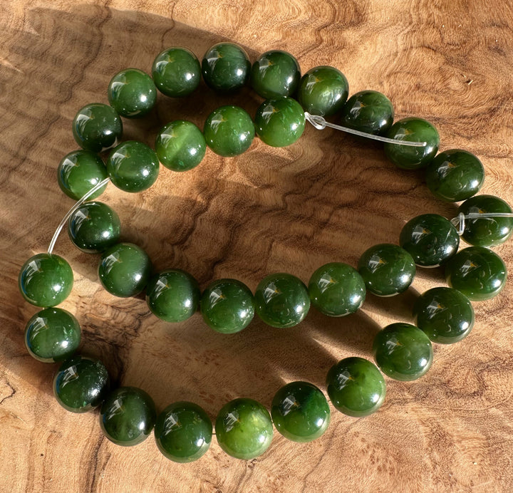 12mm Cassiar Jade unstrung beads laid on a wooden surface