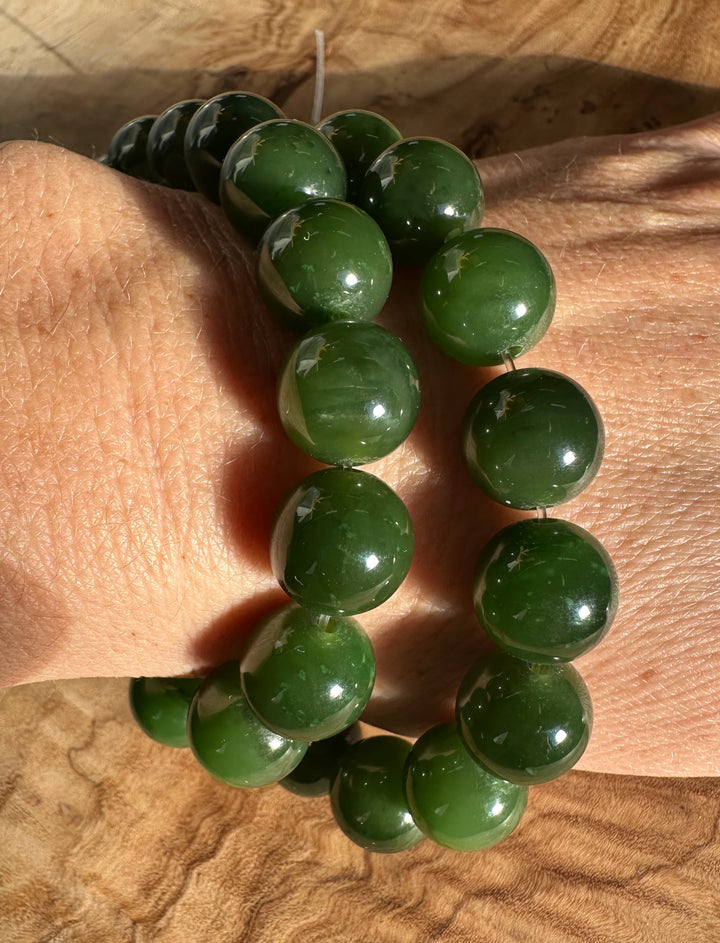 12mm Cassiar Jade unstrung beads wrapped around a wrist in glossy deep green