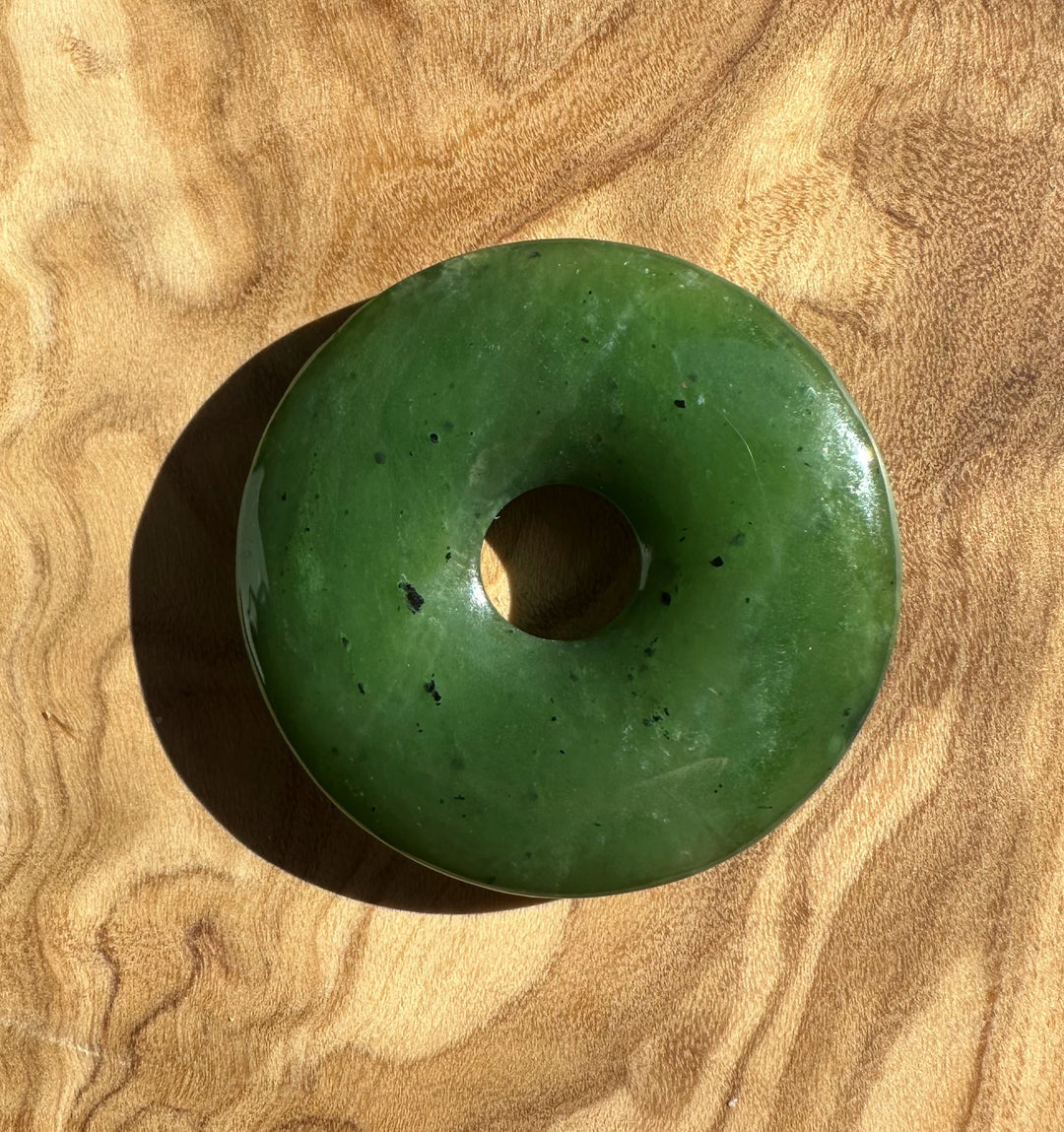 Donut shaped Canadian jade bead 37mm on a wood surface