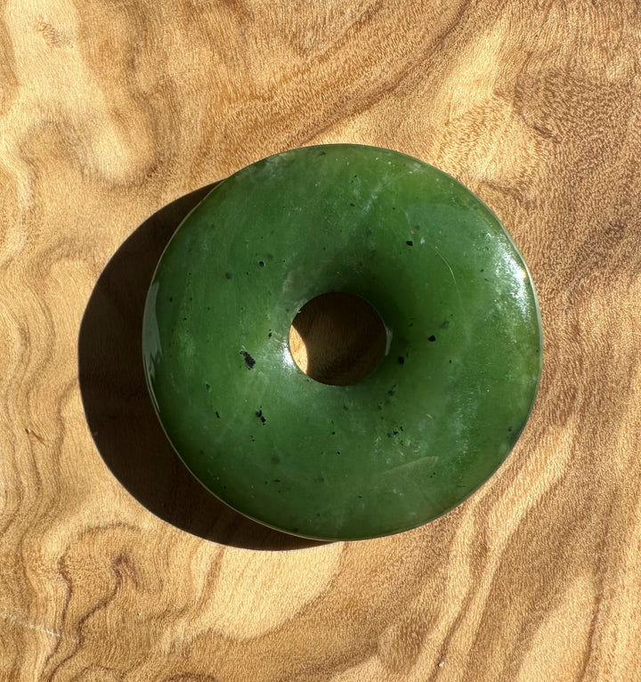 Donut shaped Canadian jade bead 37mm on a wood surface