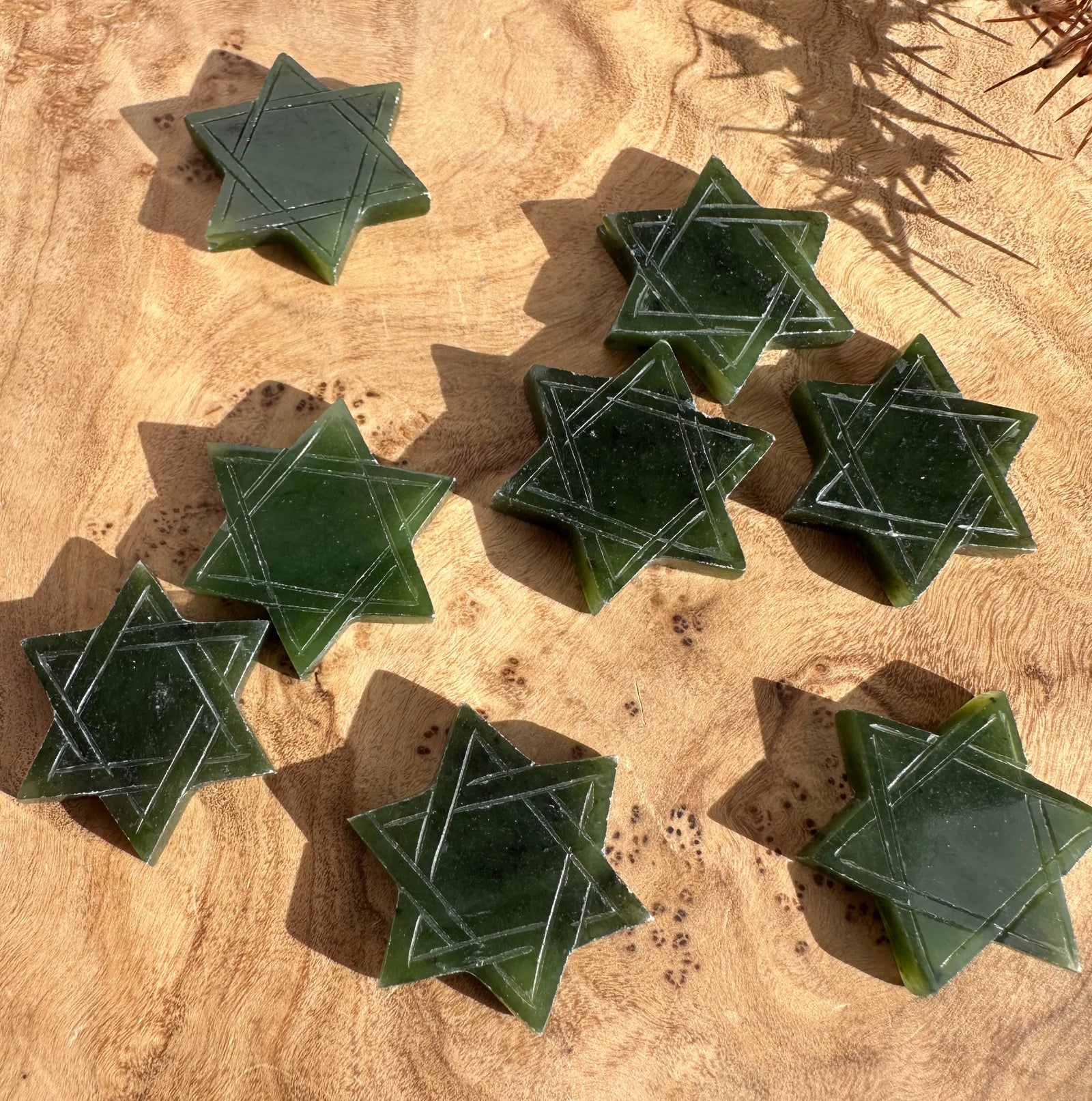 Green jade Star of David 21mm stones scattered on a wooden surface