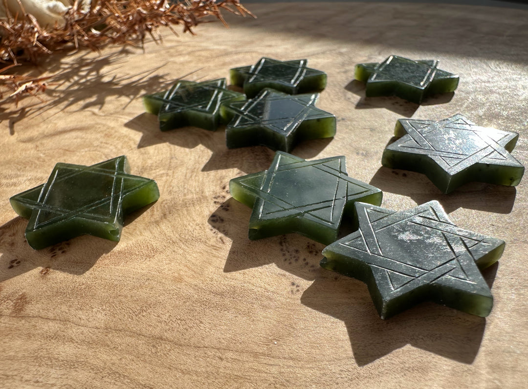 Vintage jade Star of David pendant with etched lines on a wooden surface