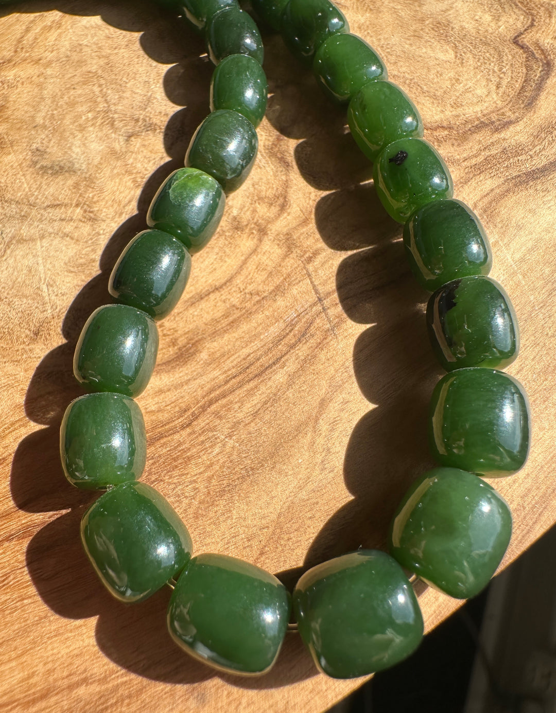 Up close of Dark Green Jade barrel shape beads on a wooden base